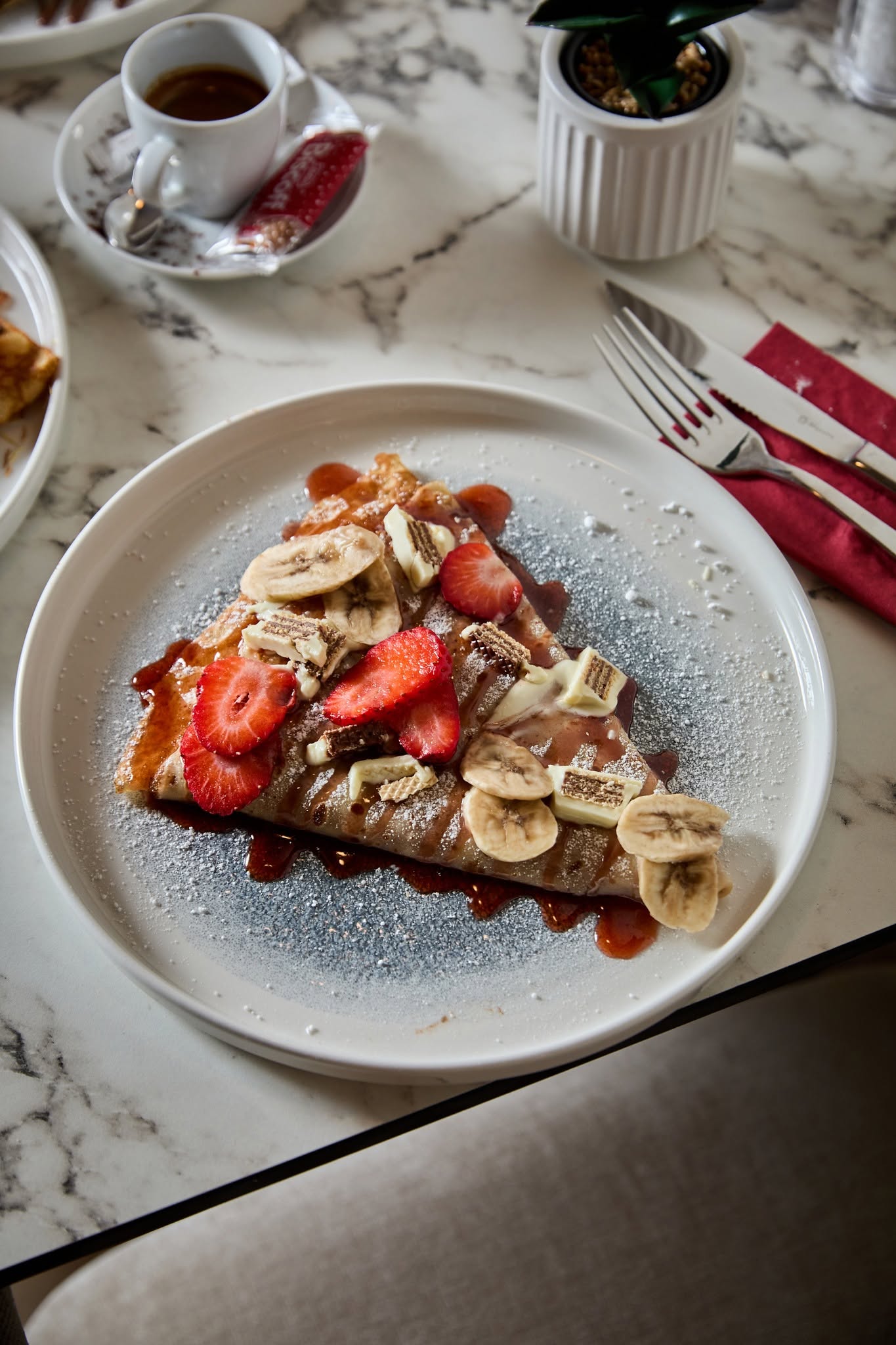 Madame Monsieur sweet crepe with strawberries, bananas, and white chocolate served with espresso in Budapest